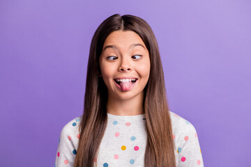 Photo portrait of goofy child showing tongue looking at nose isolated on vivid violet colored background