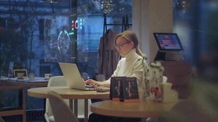 Additional reality and holographic interface. Young business woman works remotely in a cafe with a laptop, views information on a holographic screen