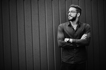 Middle eastern entrepreneur wear blue shirt, eyeglasses, against steel wall.