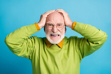 Photo Of Aggressive Retired Old Man Hands Head Mad Look Wear Glasses Green Sweater Isolated Blue Color Background