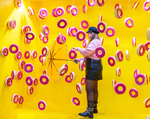 young woman with umbrella between flying donuts