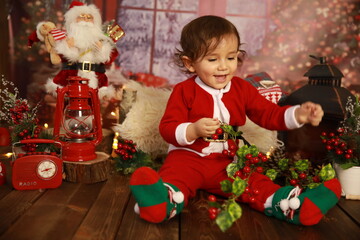 Little 1 year old boy in red santa costume near the christmas tree is playing,  Christmas, New Year 2021