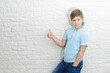© yana_novak22 - boy of european appearance in a blue shirt on a light background shows thumbs up, concept of approval