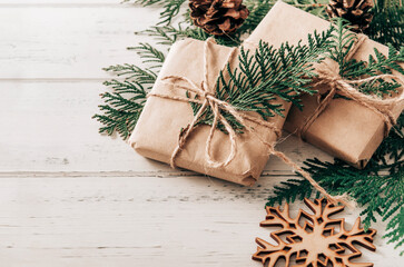 2 Christmas gift boxes with fir branches,  snowflake  and cones on a white wooden background,