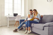 © Studio Romantic - Happy parents and kid sitting on sofa, reading book of stories or looking through family photo album