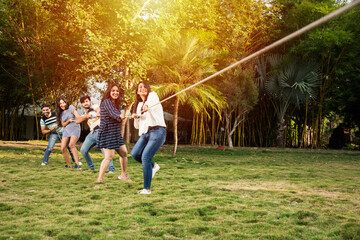 Indian asian young friends playing tug of war or rassi khech outdoors