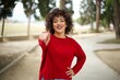 © Roquillo - Young arab woman wearing casual red sweater in the street, pointing at camera with a satisfied, confident, friendly smile, choosing you