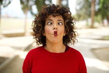 Young Arab Woman Wearing Casual Red Sweater In The Street, Making Fish Face With Lips, Crazy And Comical Gesture. Funny Expression.