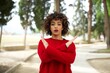 © Roquillo - Young beautiful Arab woman standing outdoors wearing red sweater Rejection expression crossing arms doing negative sign, angry face