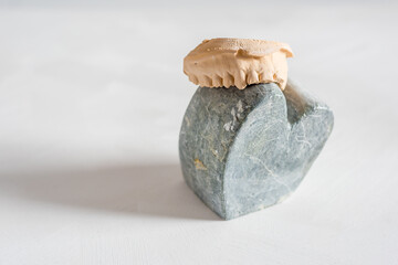 Closeup shot of heart-shaped stone with teeth molder against a white background