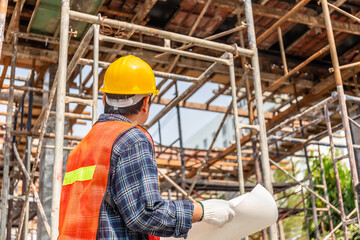 Worker man in hard hat holding blueprint checking and planning project at construction site