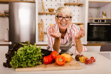 Wall Mural - Happy senior woman cooking in her modern kitchen