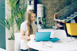 © Ilona - Young woman working on a laptop in a cafe at a table. Businesswoman, freelancer, remote work.