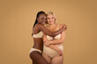 Two body positive ladies in underwear embracing and smiling at camera