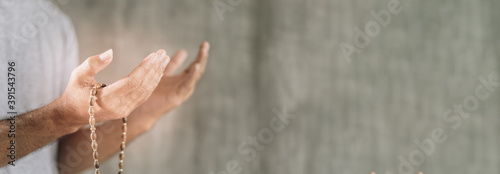 Fotografía Muslim man praying with rosary beads in hand against grey wall background with c