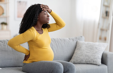 Canvas Print - African american pregnant woman suffering from headache at home