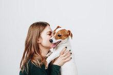 Cute Young Woman Kisses And Hugs Her Puppy Jack Russell Terrier Dog. Love Between Owner And Dog. Isolated On White Background. Studio Portrait.