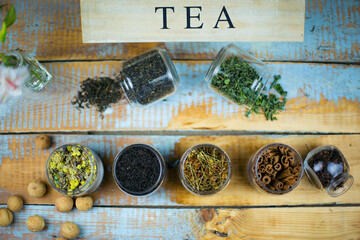 Poster - High angle shot of herbal tea leaves and cinnamon in jars on the table