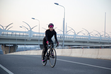 View of a girl exercising on a bicycle in the city in the morning at dawn. St. Petersburg Krestovsky Island Yakhtenny Bridge.