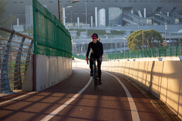 Wall Mural - Morning exercise of a woman on a bike in the city. Outdoor sports. Krestovsky Island Saint Petersburg Russia.