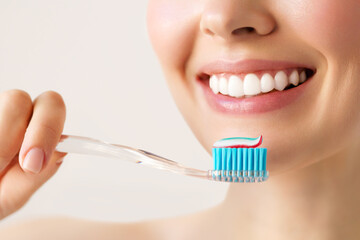 Wall Mural - Woman with healthy white teeth holds a toothbrush and smiles. Oral hygiene concept