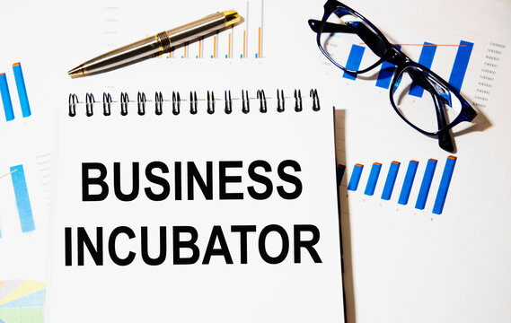 In the notebook the text business INCUBATOR, next to graphics, glasses.