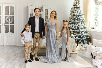 beautiful family in room with decoration near shiny Christmas tree