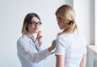 © SHOTPRIME STUDIO - Woman cleaning lady in a medical gown listens to the patient's heartbeat on a light background