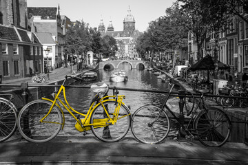 Wall Mural - A fresh yellow bike on the streets of Amsterdam. Symbol for clean and ecological urban transport. Isolated in a black and white background. 