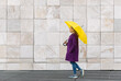 © Juan Rodríguez - Woman walking with a yellow umbrella on a stone architecture background
