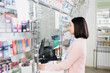© LIGHTFIELD STUDIOS - side view of asian customer holding bottles with pills near seller in drugstore