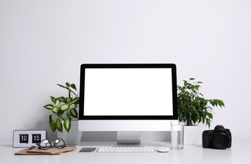 Comfortable workplace with modern computer on table near white wall. Space for text