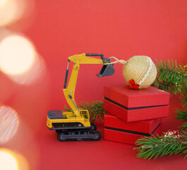 Wall Mural - model of a toy excavator, gift boxes and Christmas ball on a red background. Concept for Christmas business greetings