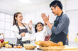 © Art_Photo - Portrait of enjoy happy love asian family father and mother with little asian girl daughter child having fun cooking together with baking cookies and cake ingredients on table in kitchen