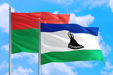 Wall Mural - Lesotho and Burkina Faso national flag waving in the windy deep blue sky. Diplomacy and international relations concept.