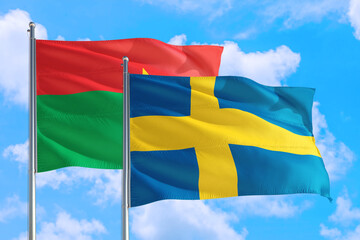 Wall Mural - Sweden and Burkina Faso national flag waving in the windy deep blue sky. Diplomacy and international relations concept.