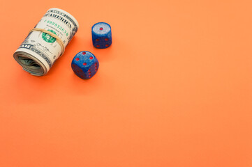 Sticker - Bundle of rolled-up American banknotes and two blue dice isolated on orange background