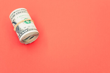 Poster - Bundle of rolled-up American banknotes isolated on a pink background