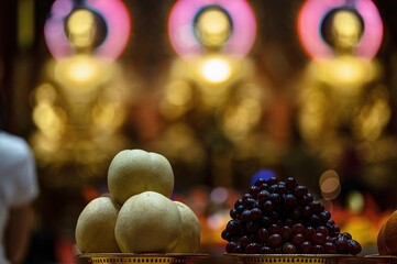 Wall Mural - Sensitive focus image of Chinese pears and Red grapes on blurred Chinese shrine background.