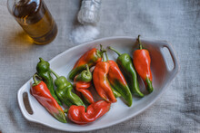 High Angle Shot Of Red And Green Jalapeno Peppers In A Bowl On The Table With Salt And Oil On It