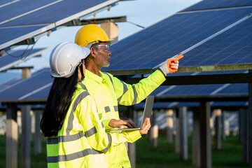 Poster - Two electrician workers in reflective vests and hard hats working at solar panels and talking about installation of new solar panels,Concept of alternative energy and its maintenance.