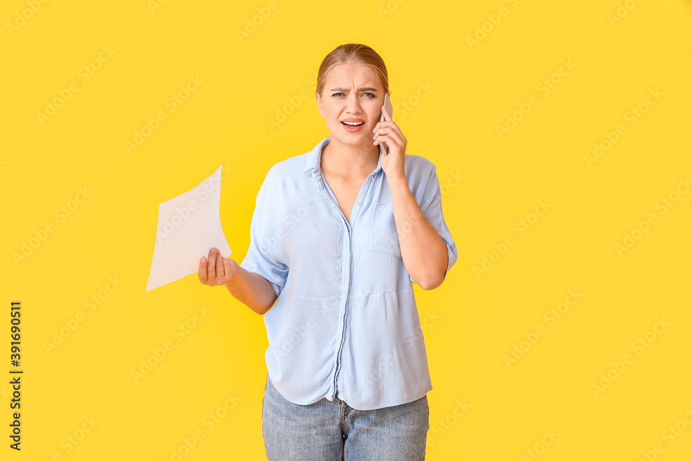Stressed young woman talking by mobile phone on color background