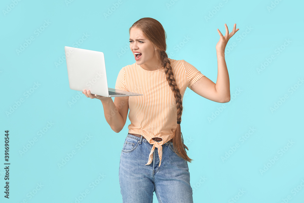 Stressed young woman with laptop on color background