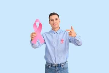 Wall Mural - Man with pink ribbons on color background. Breast cancer awareness concept