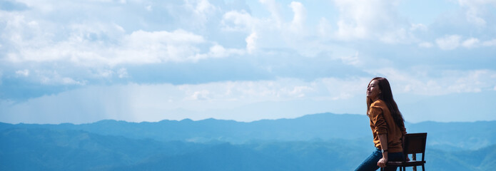 Portrait image of a female traveler looking at a beautiful mountain and nature view