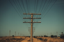 Wood Pole And Crossarms Support Electrical Wires In Rural Setting, Against The Blue Sky