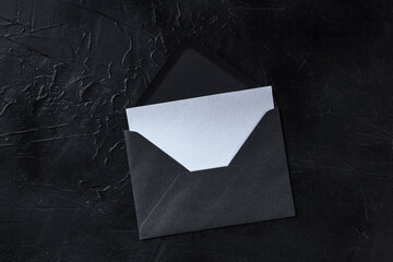Wall Mural - A greeting card in a black envelope mockup, shot from above on a dark background with copy space