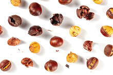 Roasted Chestnuts In Various Stages Of Peeling, Shot From The Top On A White Background, A Flat Lay