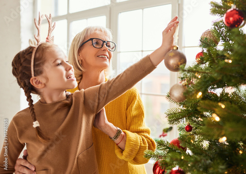 Fotografía Mature woman and girl decorating Christmas tree together
