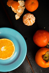 Wall Mural - Orange persimmon and tangerine on black background